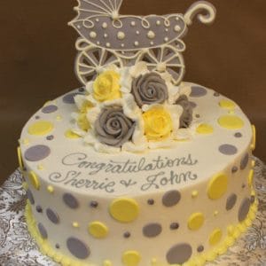 The BB-062 is a round cake decorated with yellow and gray polka dots, topped with gray and yellow roses plus a baby stroller decoration. "Congratulations Sherrie & John" is written in script icing.