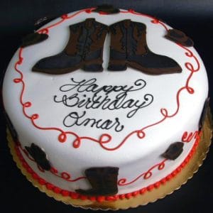 The cb-033 is a round white birthday cake with cowboy boot decorations, red icing swirls, and "Happy Birthday Omar" written in black icing on top.