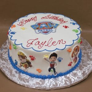 CB-009H: Round birthday cake with Paw Patrol logo, colorful paw prints, and characters. “Happy Birthday Jaylen” is written on top in blue and red icing. Cake is presented on a silver tray.