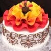 The THX-026 cake is round with white icing, decorated with chocolate flower piping, colorful dots, large red, orange, and yellow ribbon-like fondant on top, and a small turkey figure at the center.
