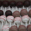 CO-030 Red Velvet Cake Pops, coated in dark, milk, and white chocolate and drizzled with red icing, are arranged neatly in a box.