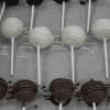 CO-031 Gold Cake Pops are displayed in rows on parchment paper, featuring chocolate and white chocolate pops on sticks, some topped with decorative drizzle.