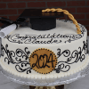 The GC-018 is a round graduation cake with black icing, a gold 2024 plaque, "Congratulations Claude" message, and comes topped with a grad cap, diploma, and gold tassel.