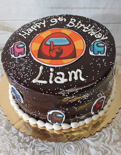 The CB-011P is a chocolate cake decorated with “Happy 9th Birthday Liam” in white icing, featuring Among Us characters and logo, and topped with white sprinkles.