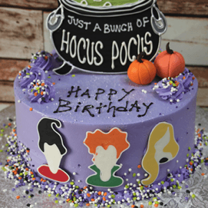 HW-018 is a purple birthday cake with sprinkles, two pumpkin toppers, a “Just a bunch of Hocus Pocus” sign, and silhouettes of three witches' heads on the side.