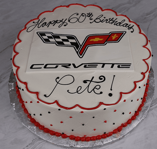 ST-015: Round white cake with red and black decorations, topped with a Corvette logo and "Happy 60th Birthday Pete!" in black icing, presented on a silver cake board.