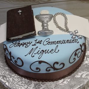 The RC-072 is a round cake with blue and brown icing, topped with fondant Bible, chalice, and rosary decorations. "Happy 1st Communion Miguel" is written in black script on the cake.