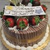 The NY-006 Chocolate Oreo is a round chocolate cake decorated with gold ribbon, chocolate-dipped strawberries, whipped cream, a small bottle accent, and a "Happy New Year 2021!" sign on top, presented on a gold cake board.