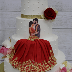 The WD-001T is a three-tier white cake with pearls, gold ribbon, red and pink roses, and a dancing couple topper. The bottom tier features red icing with gold details, mirroring the woman’s dress in the topper.