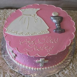 RC-039: Round pink cake with a white dress, silver chalice, “God Bless Lesley” inscription, white pearl edging, side cross detail, and presented on a silver cake board.