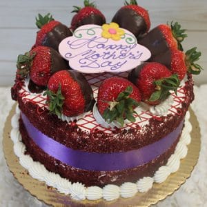 The MD-002 Red Velvet Cake is a round cake decorated with chocolate-covered and fresh strawberries, white icing, a purple ribbon, a “Happy Mother’s Day” plaque, and topped with a small yellow flower.