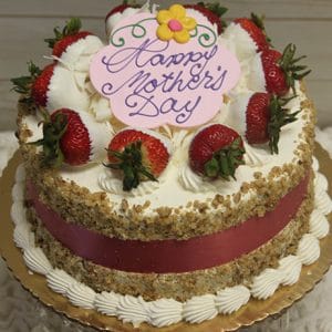 MD-006 Carrot Cake: A round cake with white cream, whole strawberries, chopped nuts on the sides, and a pink ribbon. Topped with a “Happy Mother’s Day” message on a pink plaque featuring a flower.