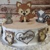 The CB-012F is a woodland-themed cake with cartoon fox, rabbit, skunk, and owl figures, rustic wood-inspired frosting, and a heart featuring the name Charlotte.