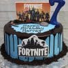 The CB-011E is a blue and chocolate drip cake with Fortnite toppers, a large blue number 7, Oreo crumbs, and a "Happy Birthday Harvey" message on a silver tray.