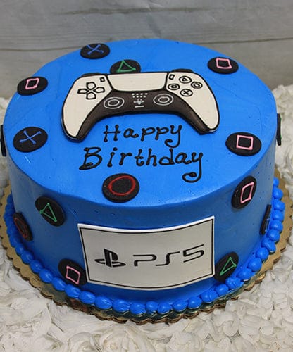 The CB-011M is a round blue birthday cake featuring PlayStation controller buttons, a controller topper, "Happy Birthday" in black icing, and a white fondant panel with the PS5 logo on the side.