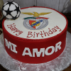 The ST-013 is a round birthday cake featuring a soccer ball, Benfica club logo, "Happy Birthday" on top, and "MI AMOR" in bold white letters on the red sides.