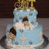 The RC-001C is a two-tier light blue cake with white crosses, cartoon angels, white flowers, and blue birds. It features a gold glitter “God Bless” topper with a cross and “God Bless Alexander!” on a white banner at the base.
