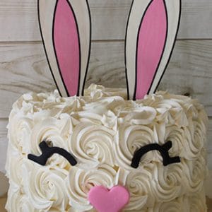 EA-029 features a cute bunny face design with white frosting rosettes, black icing eyelashes, a pink heart-shaped nose, and large bunny ears with pink centers.