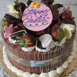 The EA-006 Chocolate Oreo Cake features strawberries, chocolate-dipped Oreos, pastel bunny chocolates, a pink “Happy Easter” topper, and piped white frosting on a gold board.