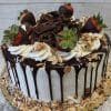 The BD-018A Almond Joy Cake is a round cake with white frosting, chocolate ganache drips, topped with chocolate-dipped strawberries, whipped cream swirls, chocolate shavings, and toasted almonds and coconut around the base.