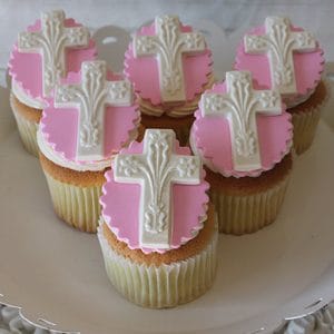 RC-100 Gold cupcakes with chocolate filling displayed on a white plate, each decorated with pink fondant and a white cross, perfect for religious or celebratory occasions.