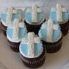CC-042 Chocolate cupcake with white chocolate mousse filling, topped with white icing and decorated with blue fondant circles and white crosses, arranged on a white plate—perfect for a religious celebration.