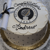 The GC-000F Bryant is a round cake featuring the Bryant University seal, "Congratulations Andrew," and a small diploma with a black ribbon, presented on a gold-edged platter.