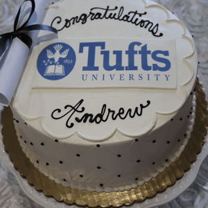The GC-000N Tufts University cake features a white design with black polka dots, a gold base, a rolled diploma decoration, “Congratulations Andrew” written on it, and the Tufts University logo on top.