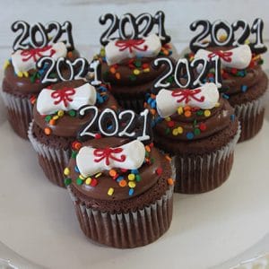 GC-071 Chocolate cupcakes with white filling topped with chocolate frosting, colorful sprinkles, a fondant diploma, red ribbon, and 2021 decoration, displayed on a white cake stand.