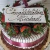 GC-004 is a decorated cake featuring a maroon ribbon, chocolate-dipped strawberries, and a white chocolate plaque with "Congratulations Michael" in cursive, finished with a rolled paper scroll on top.