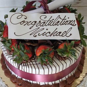 GC-004 is a decorated cake featuring a maroon ribbon, chocolate-dipped strawberries, and a white chocolate plaque with "Congratulations Michael" in cursive, finished with a rolled paper scroll on top.