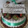 GC-006: A decorated cake topped with chocolate-dipped strawberries, a green ribbon, and a white card reading "Congratulations Michael" in cursive. Includes a rolled paper scroll tied with a green ribbon on top.
