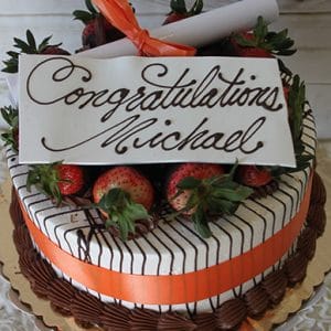 The GC-007 is a decorated cake with chocolate drizzles, strawberries, an orange ribbon, and a diploma topper. A white plaque reads "Congratulations Michael" in elegant script.
