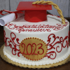 GC-015 is a round cake decorated with red and gold icing, featuring "2023" and "Congratulations Genevieve" on top, finished with a red graduation cap and diploma as toppers.