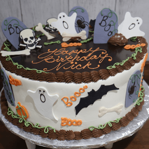 The HW-001 is a round Halloween-themed birthday cake featuring ghosts, tombstones, bats, bones, pumpkins, spiders, and "Happy Birthday Nick" written in orange icing.