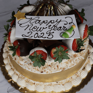 The NY-003 Pina Colada cake is a festive treat topped with chocolate-dipped strawberries, shredded coconut, gold ribbon, and a “Happy New Year 2025” plaque featuring star and champagne glass decorations.