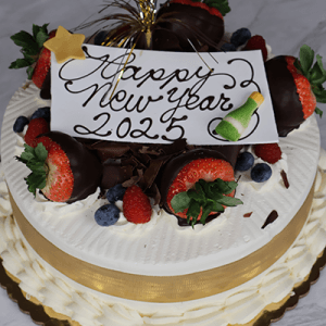 The NY-002 Tres Leche is a festive cake topped with chocolate-covered strawberries, blueberries, raspberries, a "Happy New Year 2025" chocolate sign, and a small champagne bottle decoration.