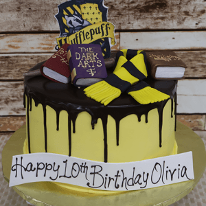 The CB-009Z is a yellow and black Hufflepuff-themed cake with chocolate drip, fondant books, scarf, crest, and a “Happy 10th Birthday Olivia” banner.