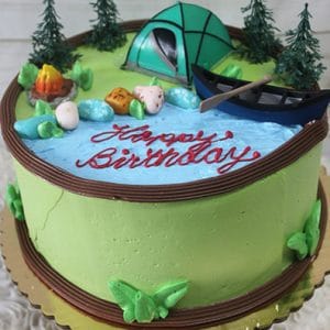 The SC-079 Camping cake is round with a camping theme, showcasing a tent, trees, canoe on a blue river, campfire, rocks, and "Happy Birthday" in red icing. The sides are covered in green frosting.
