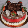 The BD-013C Chocolate Oreo is a chocolate cake topped with chocolate-dipped strawberries, chocolate shavings, white icing drizzle, piped cream at the base, and finished with a red ribbon on the sides, set on a gold cake board.