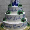 WC-019 is a four-tiered white wedding cake with purple and green flowers, blue icing that says “And they lived happily ever after,” and a blue castle silhouette on top.