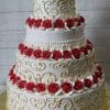 The WC-021 features a four-tier white cake with gold swirl designs and red and white frosting roses on each layer, presented on a gold cake board against a light wood background.