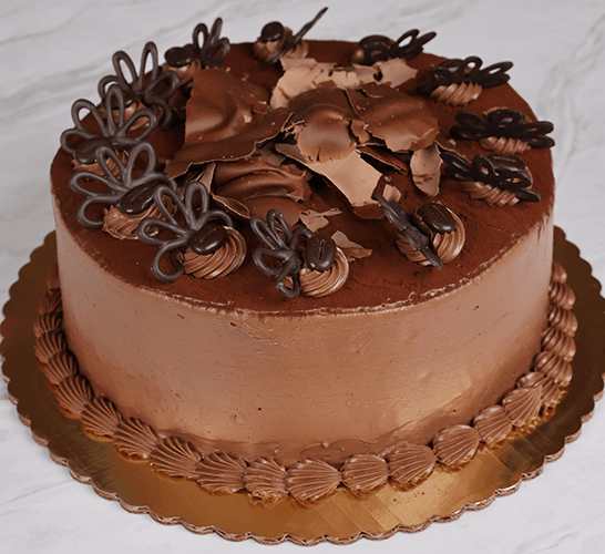 The BD-001B Tiramisu, a round cake with smooth chocolate frosting, chocolate shavings, and decorative chocolate pieces, is presented on a gold cake board against a marble background.