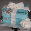 The BD-030 Designer Box cake is shaped like a Tiffany blue gift box with a white bow, "Happy 50th Birthday Connie" tag, white flower, silver key necklace, and TIFFANY & CO. written on the side.