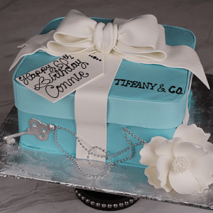 The BD-030 Designer Box cake is shaped like a Tiffany blue gift box with a white bow, "Happy 50th Birthday Connie" tag, white flower, silver key necklace, and TIFFANY & CO. written on the side.