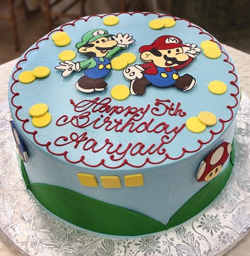 The CB-011T is a round blue birthday cake featuring Mario and Luigi, yellow coins, red "Happy 5th Birthday Aaryan" lettering, and Mario-themed designs on the sides.