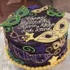 The BD-165 is a round cake with green, yellow, and purple masquerade masks and stars, finished with white icing that reads “Happy Birthday Kevin, Martyn, and David.”.