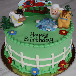 The SC-001 Farm Animals cake is round and green, decorated with a white fence, colorful flowers, cow, sheep, horse figurines, a farm scene topper, and "Happy Birthday" written on top in black icing.
