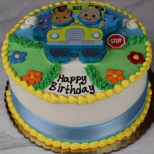 The SC-003 Cocomelon birthday cake is round, decorated with colorful icing, cartoon animal characters in a yellow bus topper, flowers, a stop sign, "Happy Birthday" text on top, and a blue ribbon wrapped around the base.