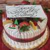 The CH-005 Display Gold Cake features lemon raspberry filling, festive Christmas decor, and a gold finish. It’s topped with strawberries, lemon slices, cream, chocolate drizzle, and a “Happy Birthday Britney” plaque in cursive.